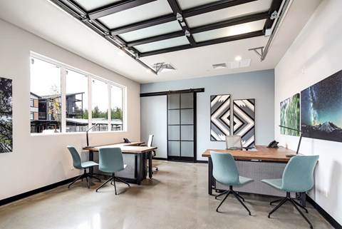 a conference room with two desks and chairs and large windows