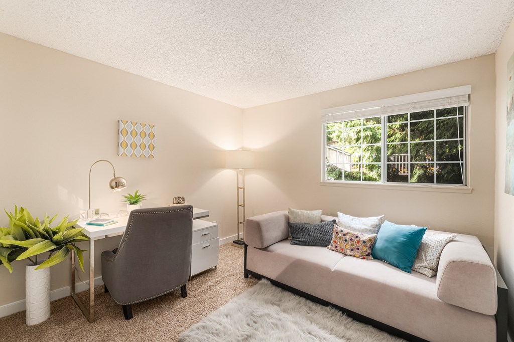 a living room with a couch and a desk and a window