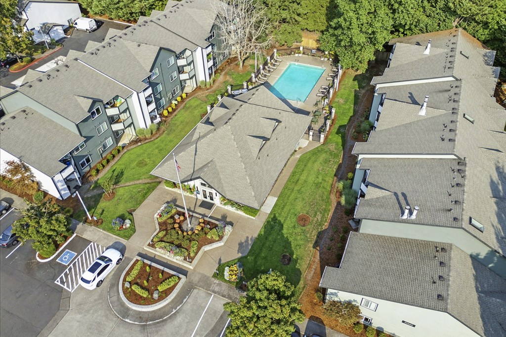 A bird's eye view of a residential area with houses, a pool, and a parking lot.