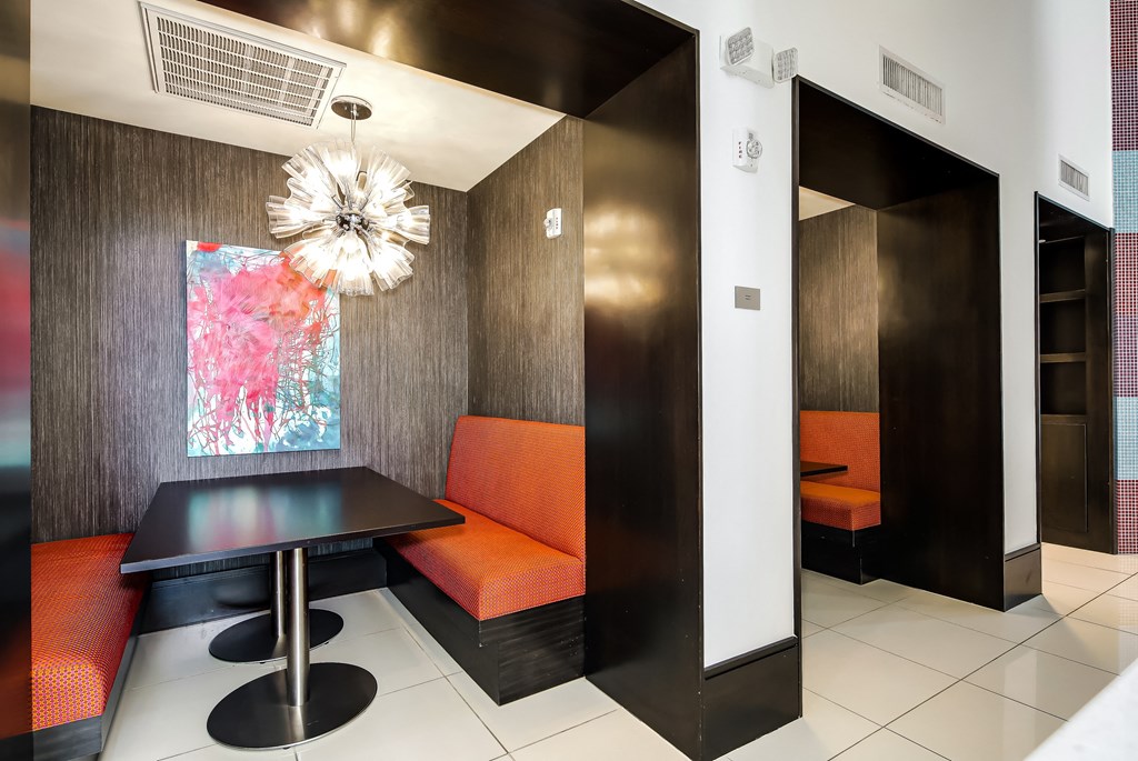 a dining area with a black table and orange chairs