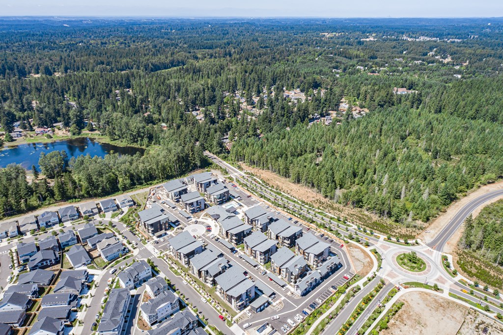an aerial view of a parking lot with houses and trees
