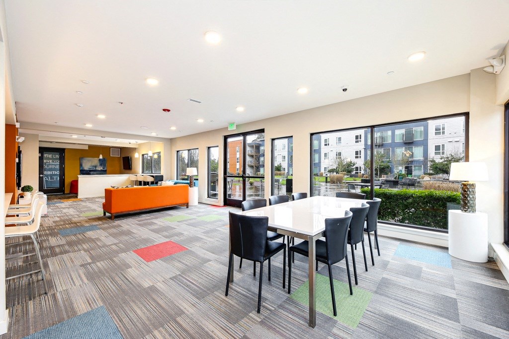 a dining room with a table and chairs in a building with large windows