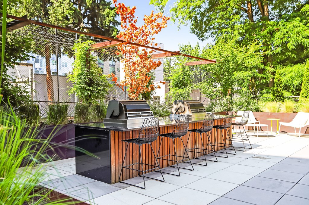a long bar with chairs and a grill in a backyard