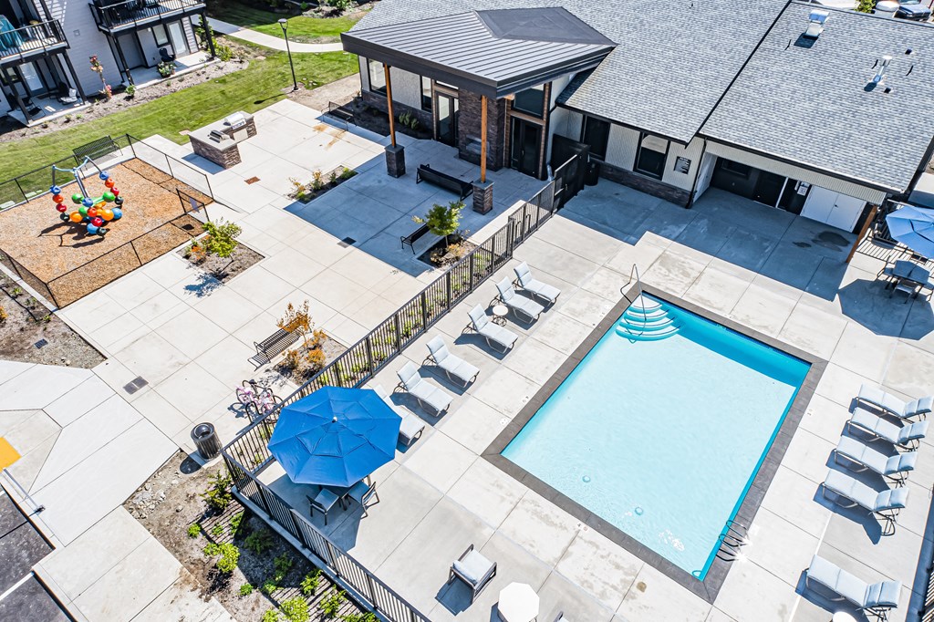 an overhead view of a swimming pool and patio with chairs and umbrellas