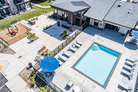 an overhead view of a swimming pool and patio with chairs and umbrellas