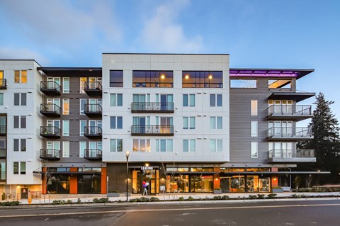 A modern multi-story building with balconies and lit windows.