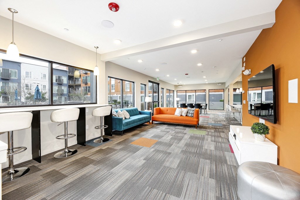 a lounge area with couches and a bar in a building with large windows