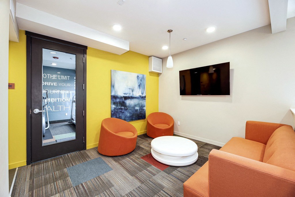 a living room with orange couches and chairs and a television