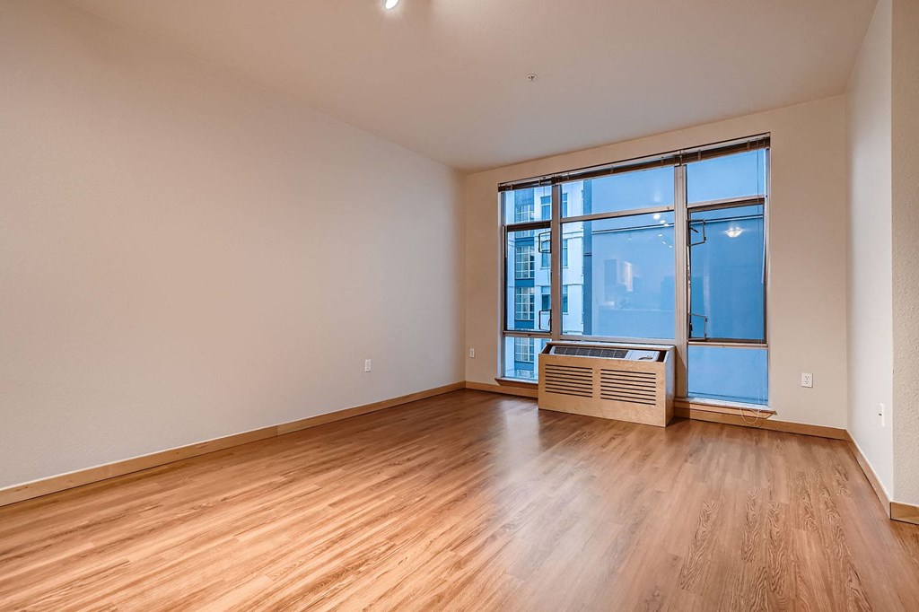 an empty living room with wood floors and a large window