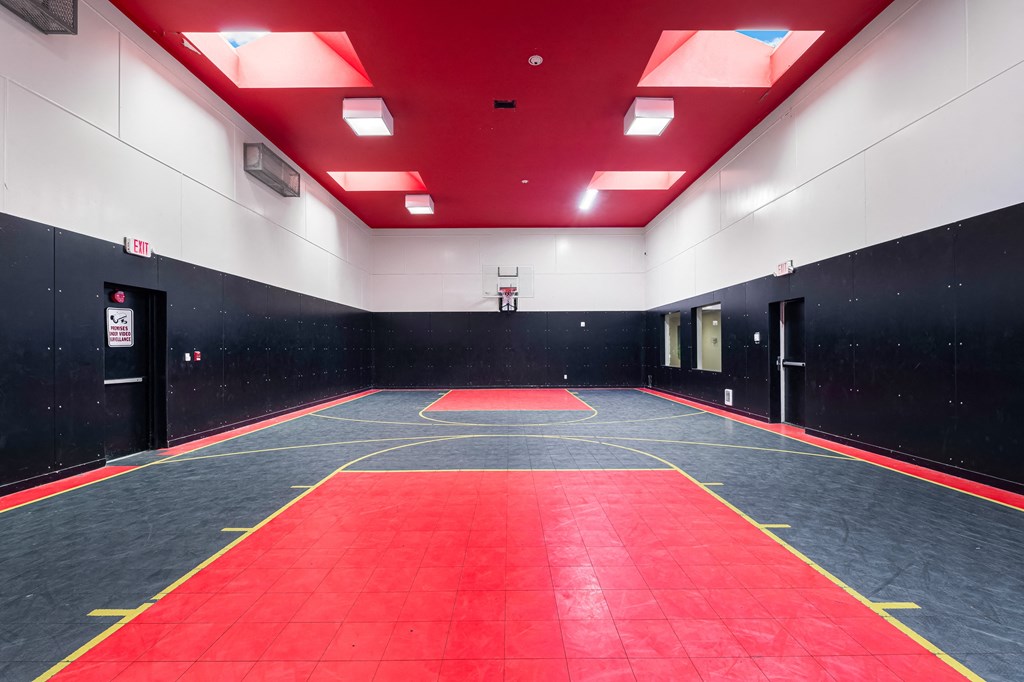 a large empty gym with a red and black wall and red carpet