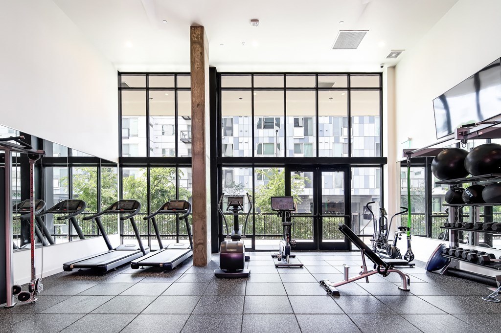 a gym with floor to ceiling windows and weights and exercise equipment