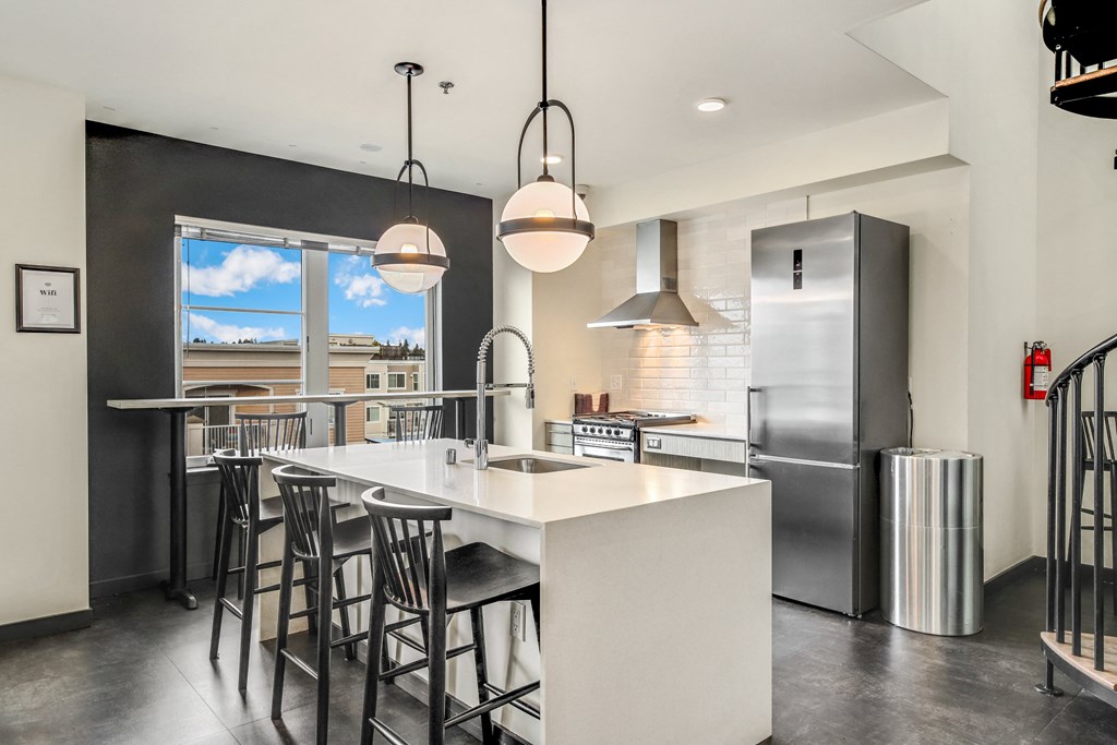 a kitchen with a large island and a stainless steel refrigerator