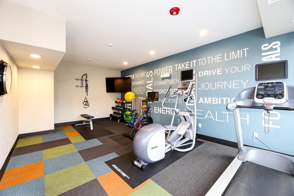 a gym with exercise equipment and a wall with a quote on it