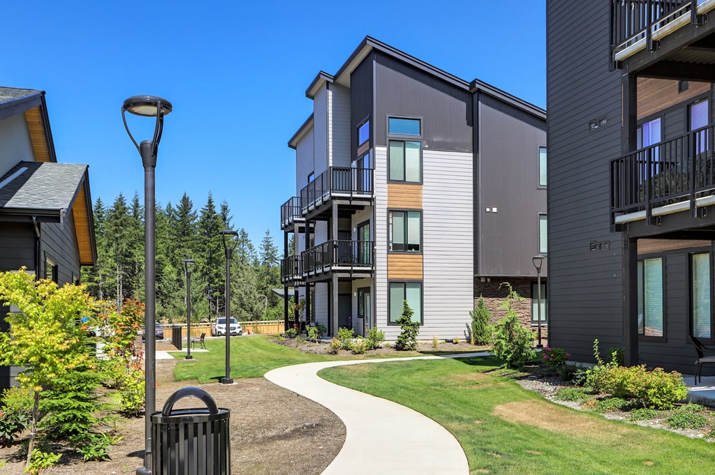 a walkway between two buildings with trees in the background