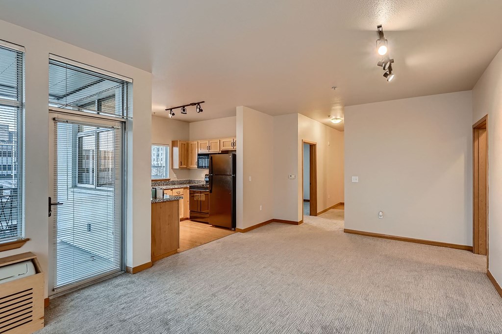 an empty living room with a door to the kitchen