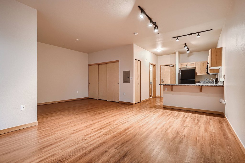 an empty living room and kitchen with wood floors