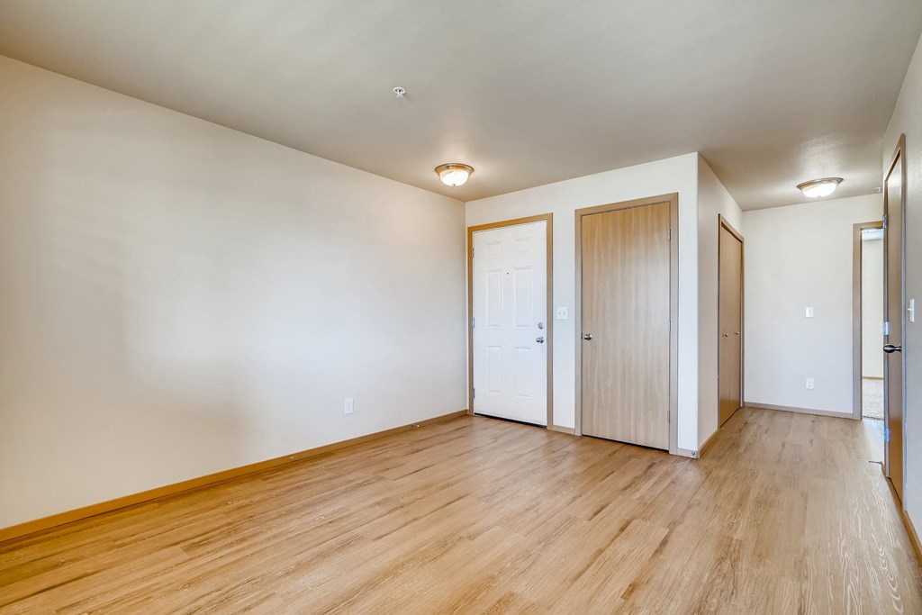 A room with wooden floors and white walls with three doors.