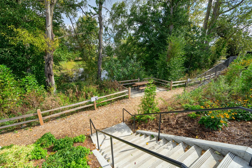 A set of stairs with a metal railing lead up to a wooden deck.