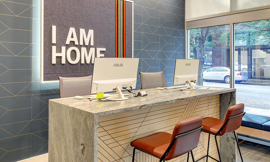 a desk with four chairs in a room with a sign that says i am home