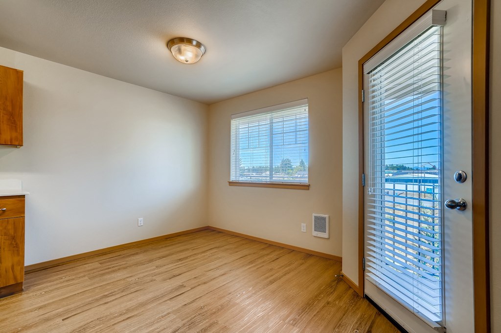 A room with wooden floors and a window with blinds.