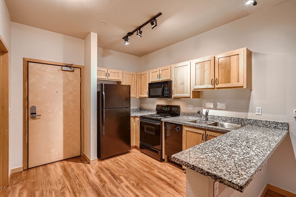 a kitchen with granite counter tops and a stainless steel refrigerator