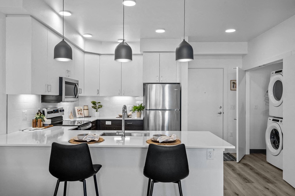 an open kitchen with a counter and two black chairs
