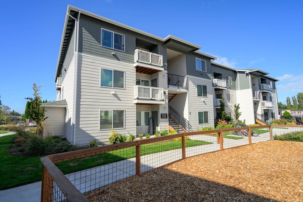 A modern apartment building with a fenced in courtyard.