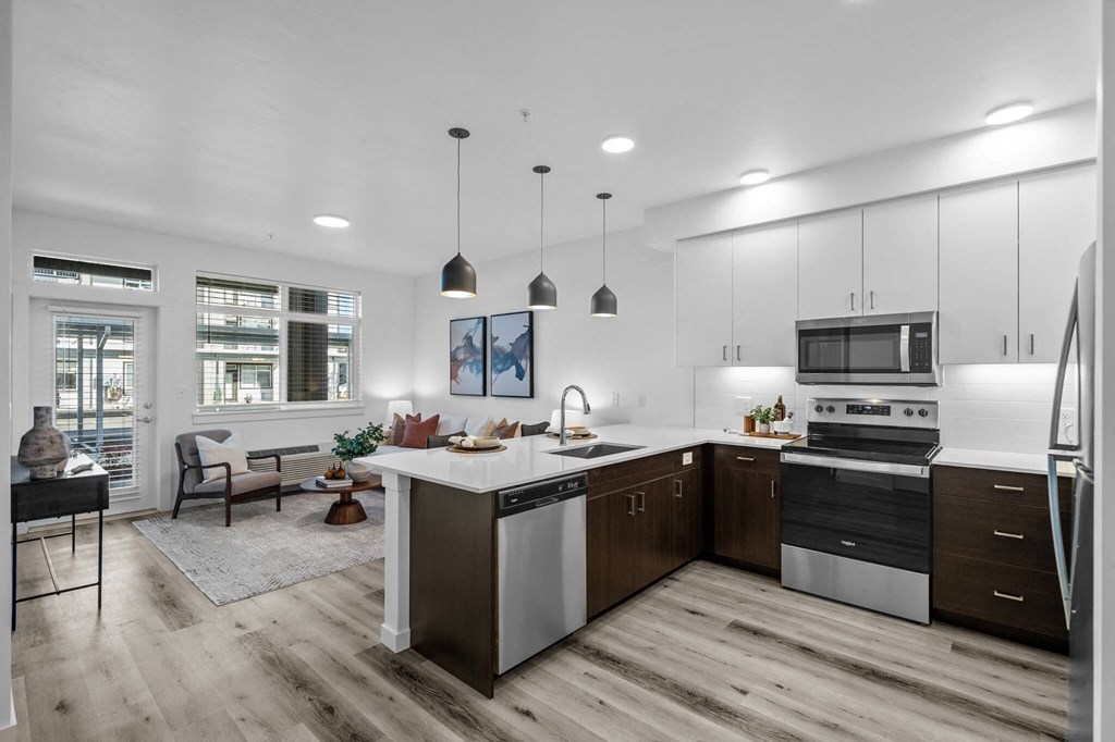 an open kitchen and living room with white cabinets and stainless steel appliances