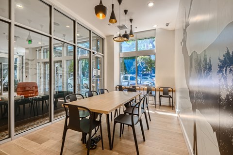 a long table with chairs in a room with large windows