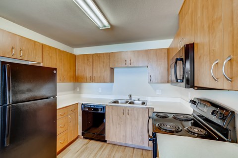 A kitchen with wooden cabinets and a black refrigerator.