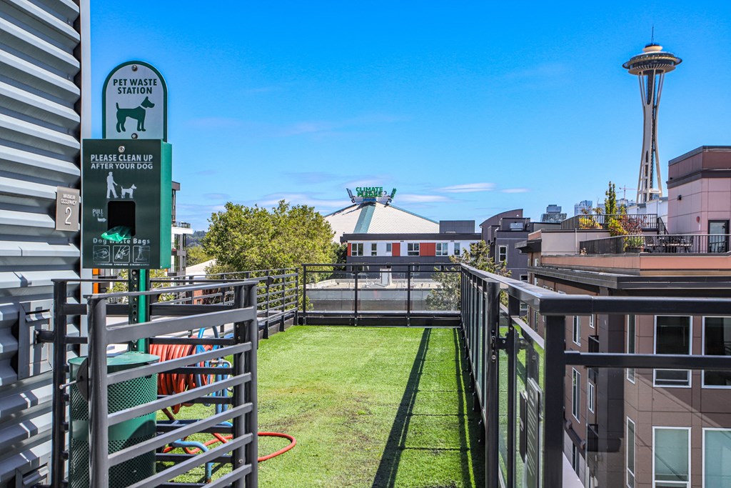 the grassy roof terrace of a building with a dog park and a sign