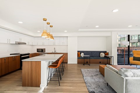 A modern kitchen with a white island and a grey sofa.