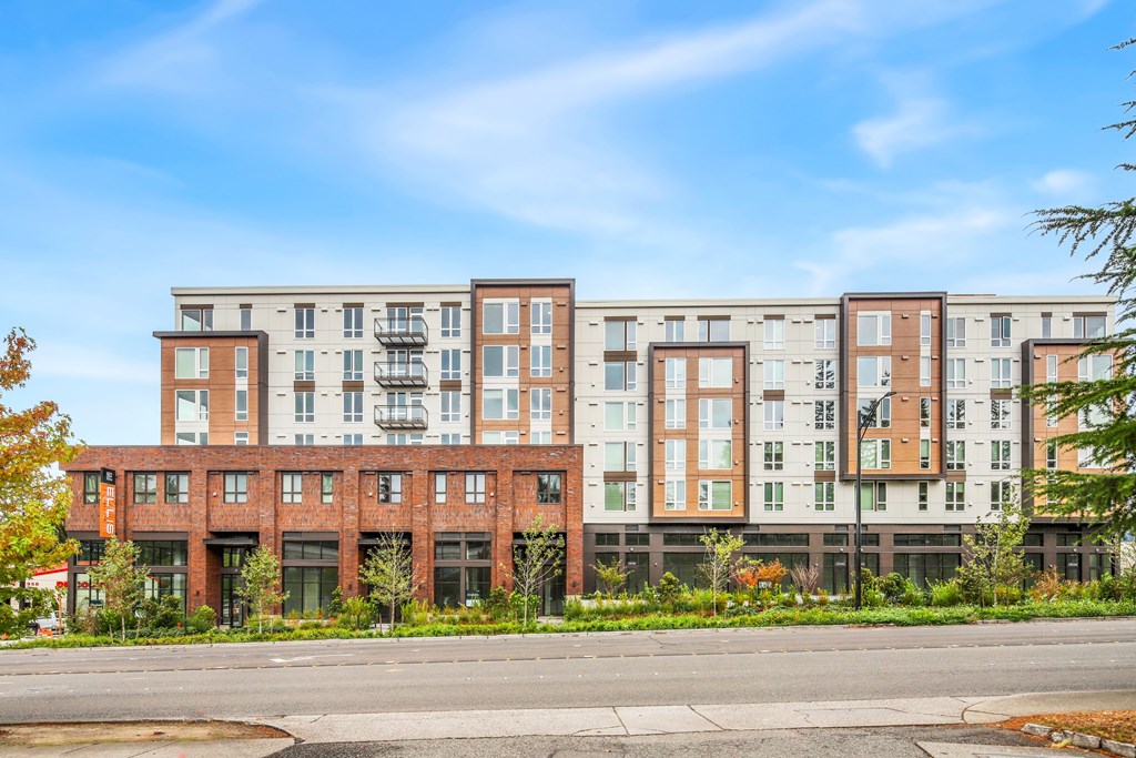 A row of modern apartment buildings with trees in front.
