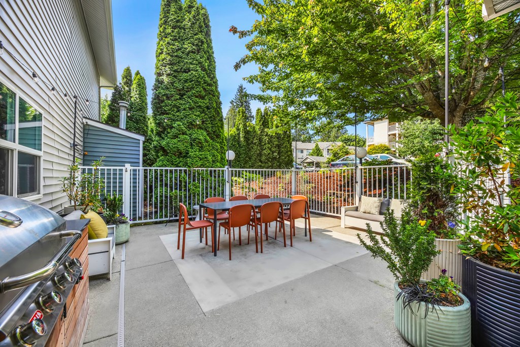 A patio with a table and chairs surrounded by a fence and trees.