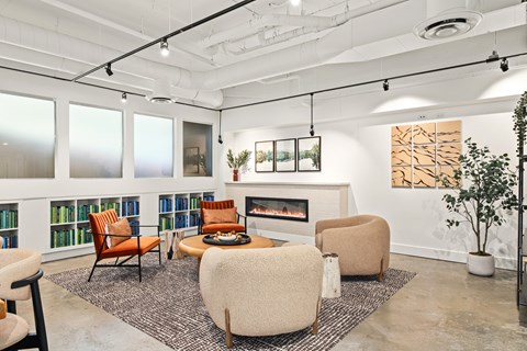 A living room with a fireplace, chairs, and a rug.
