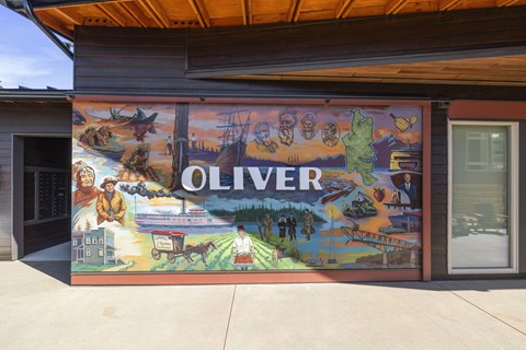 A mural on a building wall depicts the history of Oliver.