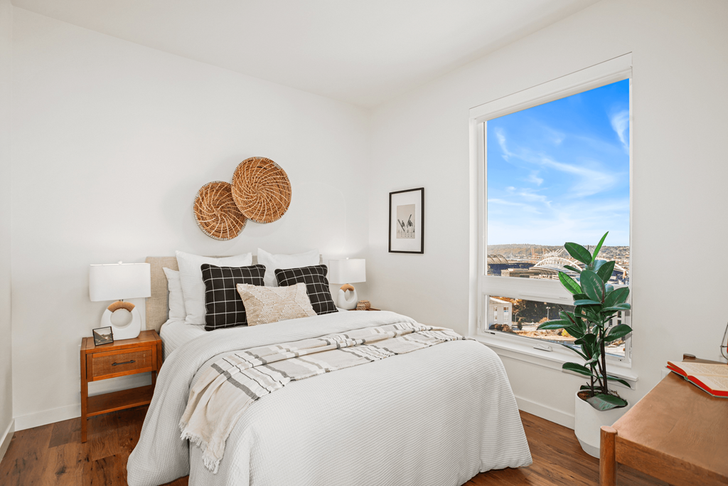 A bedroom with a large bed and a window overlooking a cityscape.