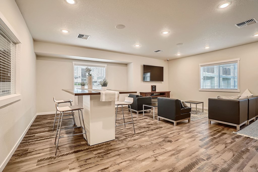 a living room with a kitchen and a bar with chairs