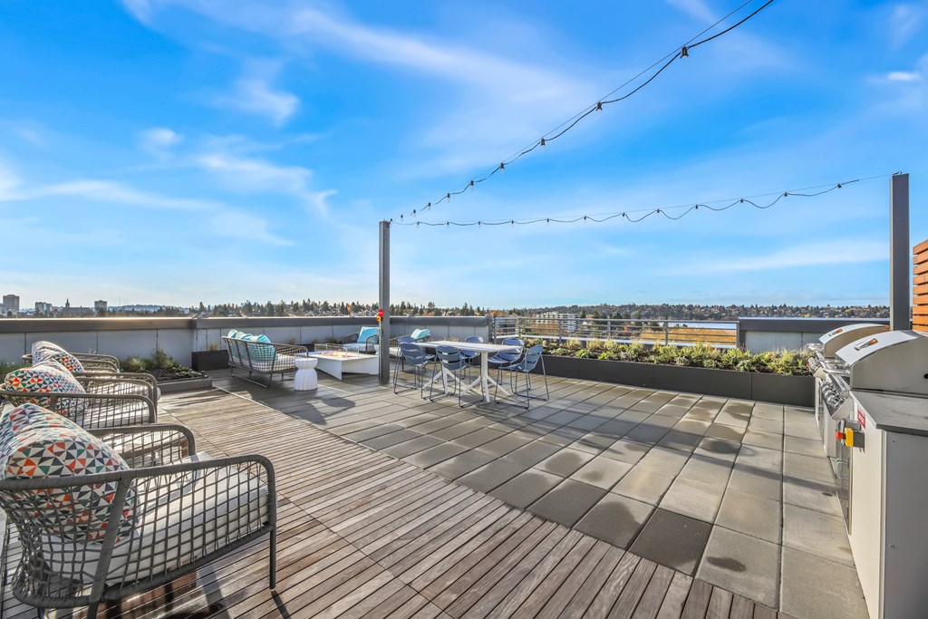 A rooftop patio with a wooden floor and outdoor furniture.