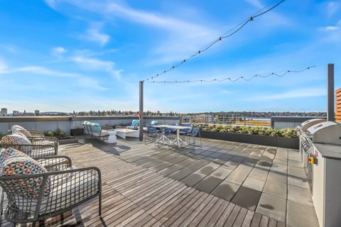 A rooftop patio with a wooden floor and outdoor furniture.