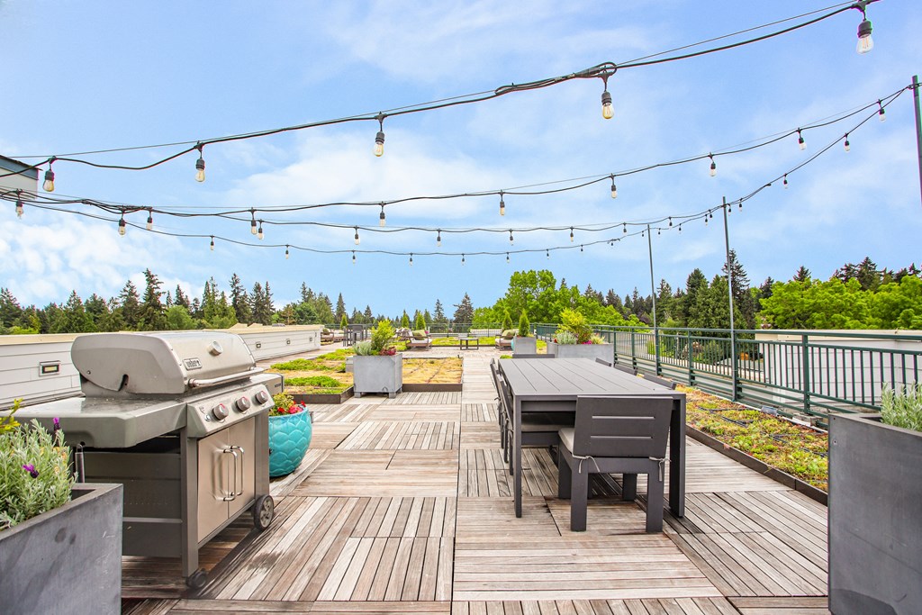 the deck is equipped with a grill and a table with chairs