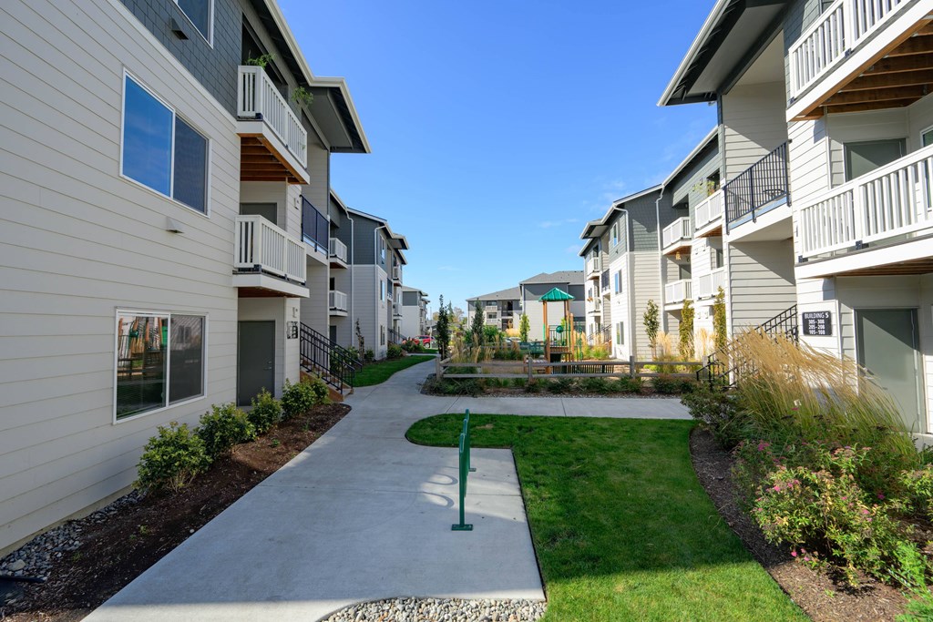 A sunny day at a residential apartment complex with a walkway between the buildings.