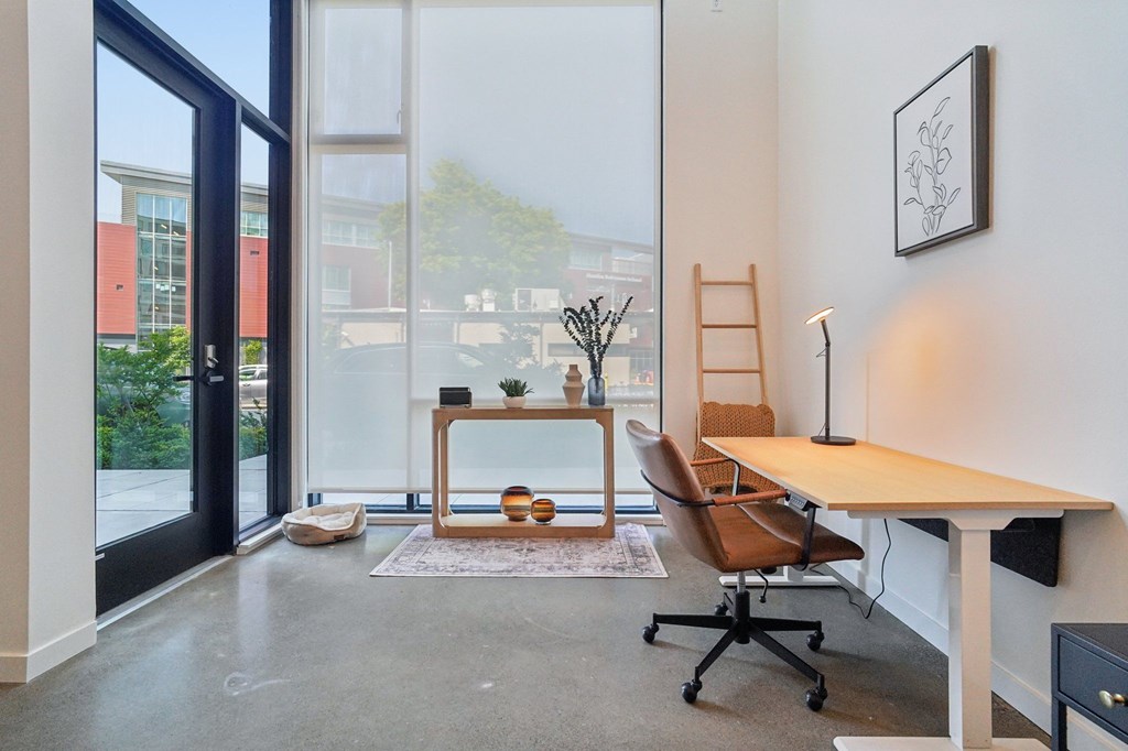 A room with a desk, chair, and a window overlooking a building.