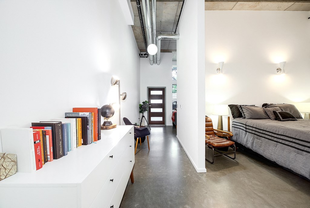 A room with a bed, a bookshelf, and a chair.