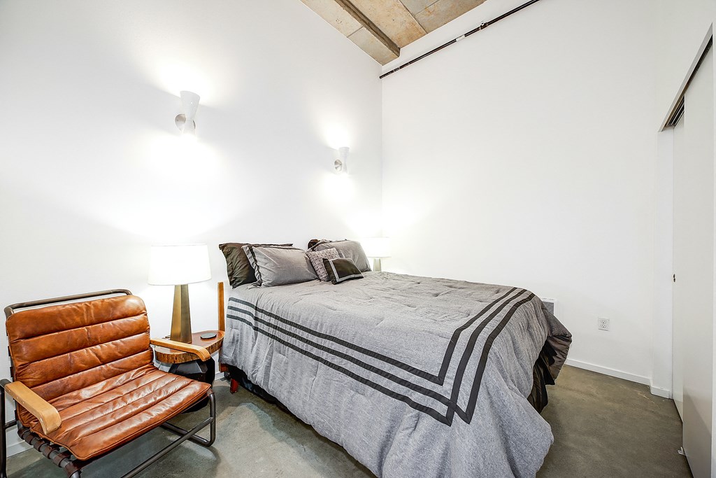 A bedroom with a bed, a chair, and a lamp.