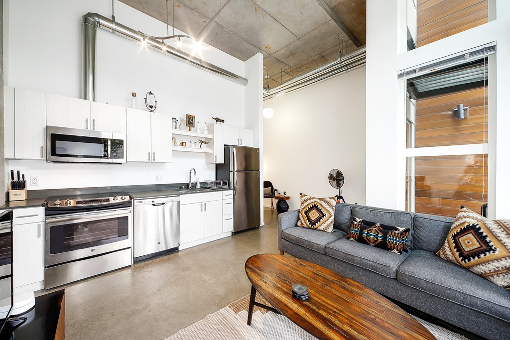 A modern kitchen with a grey couch and a wooden coffee table.