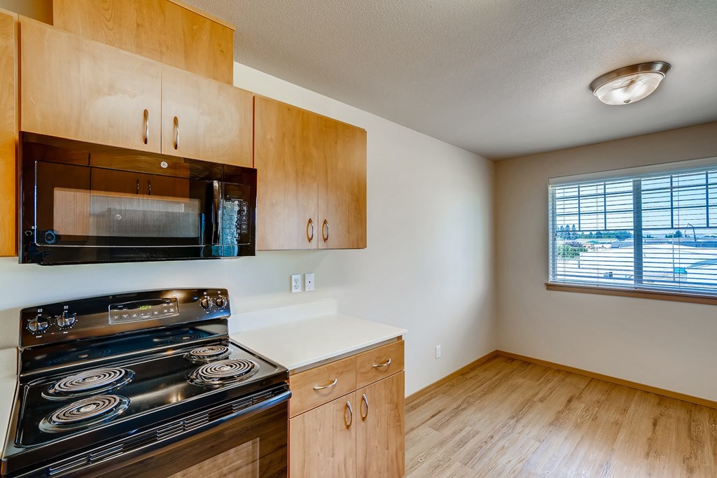 A kitchen with wooden cabinets and a black stove top oven.