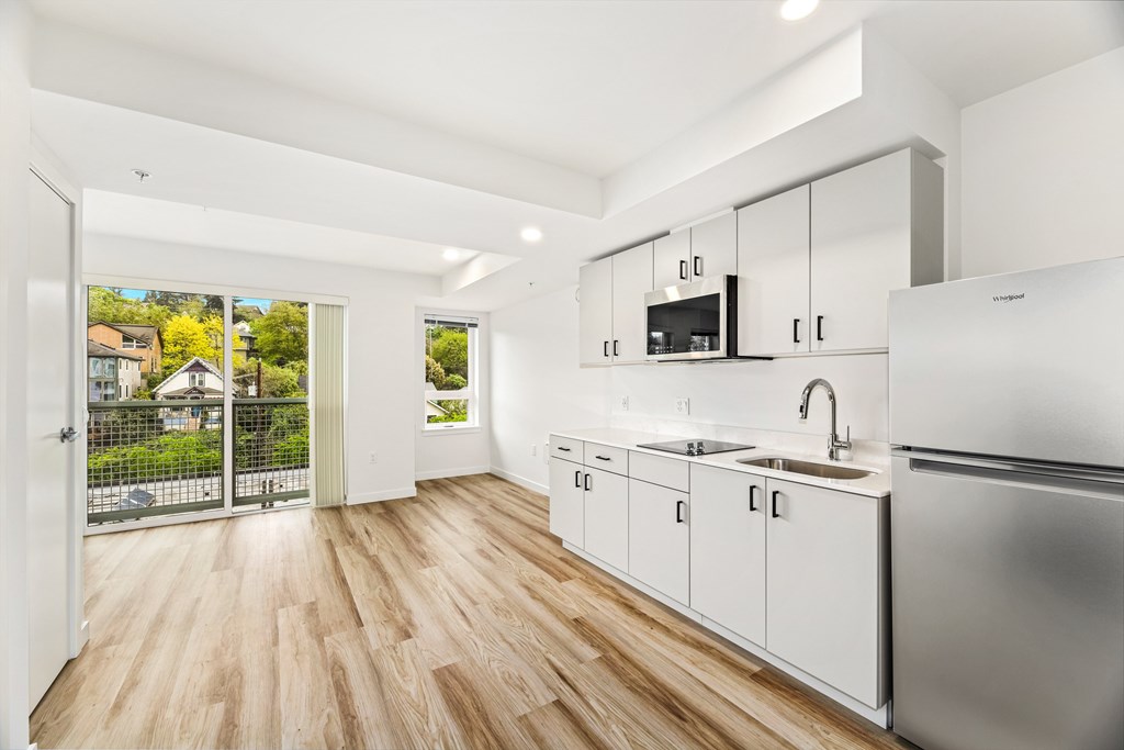 A modern kitchen with white cabinets and a wooden floor.