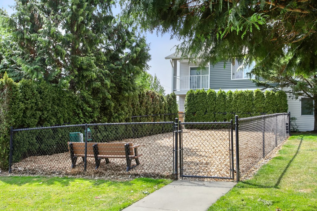 A park bench sits in front of a chain link fence.