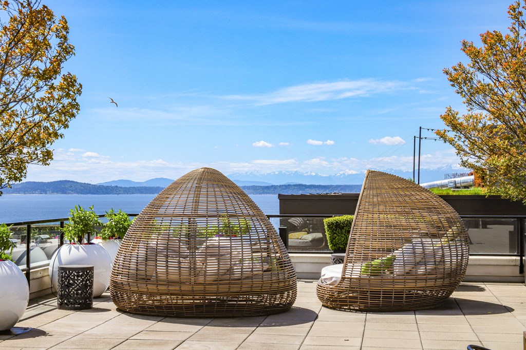 two rattan chairs sitting on a patio overlooking the water